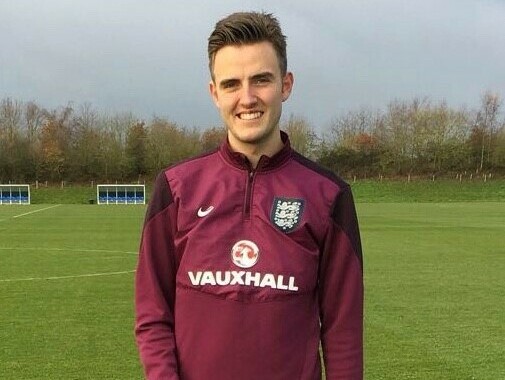 Bailey wearing his football kit standing in a field and smiling