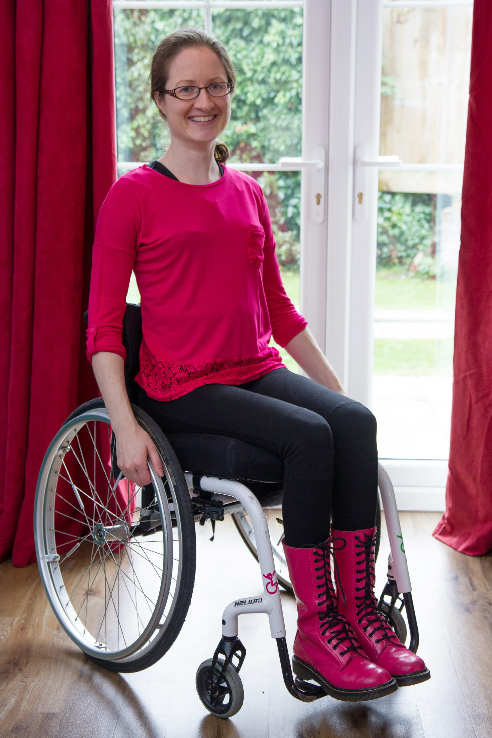 hannah sat in her wheelchair in a bright pink top smiling