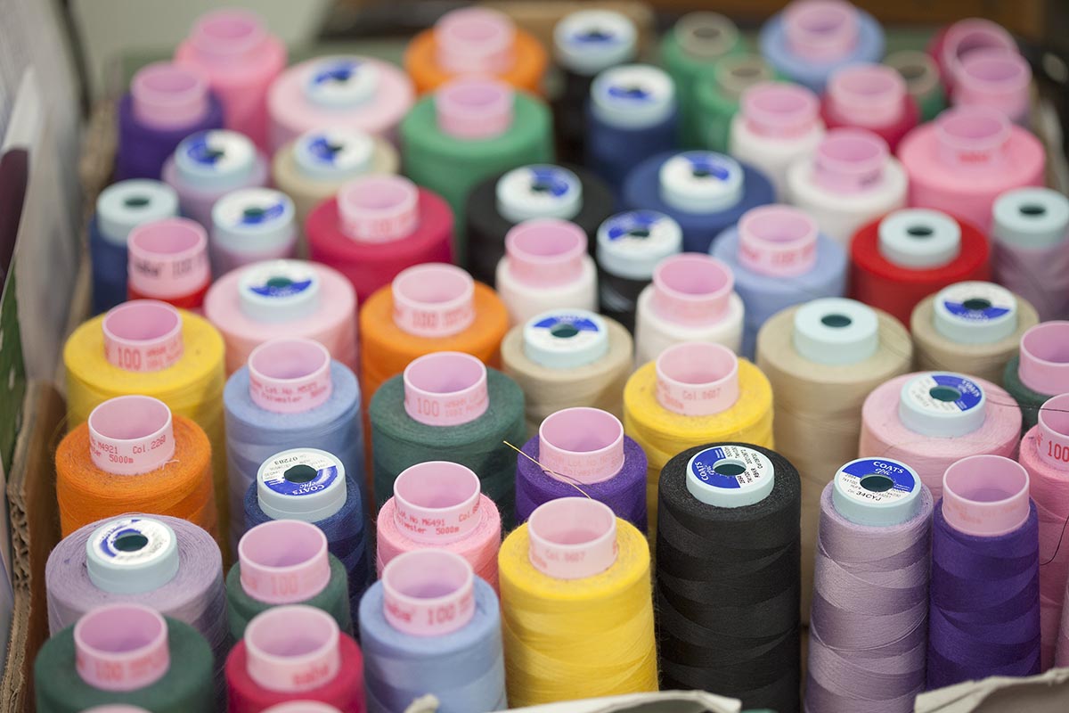 lots of spools of cotton in various colours sat next to each other in a box.